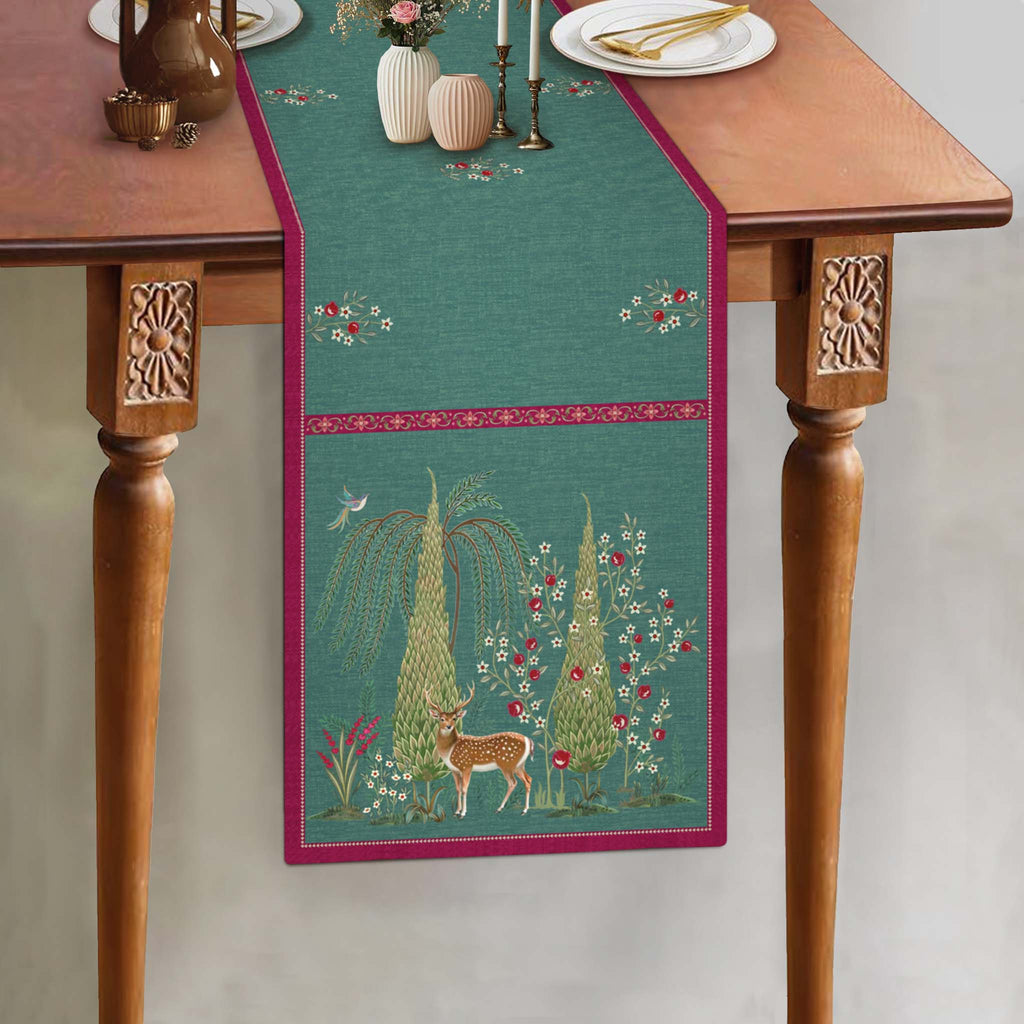 Aqua blue botanical table runner featuring an intricate deer motif, delicate floral illustrations, and a contrasting berry-pink border, showcasing the Whispering Grove design by Preetier.