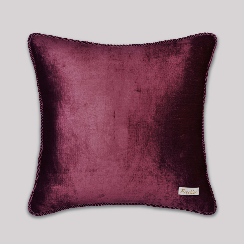 Purple velvet pillow with a brand label on a light gray background