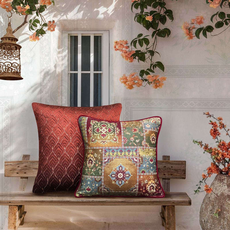 Luxury Rang Mahal cushion cover in rust and multicolor patchwork design, featuring intricate traditional print and premium fabric, styled on a wooden bench with floral decor for elegant living room interiors.